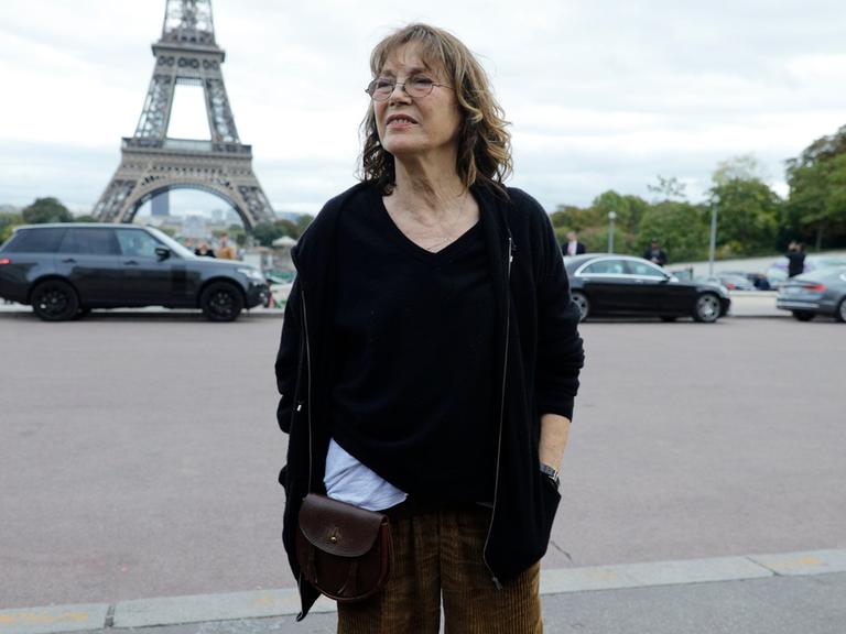 Jane Birkin steht im Oktober 2017 vor dem Eiffelturm. Sie trägt eine braune Kordhose und einen schwarzen Pulli im Oversized-Look.