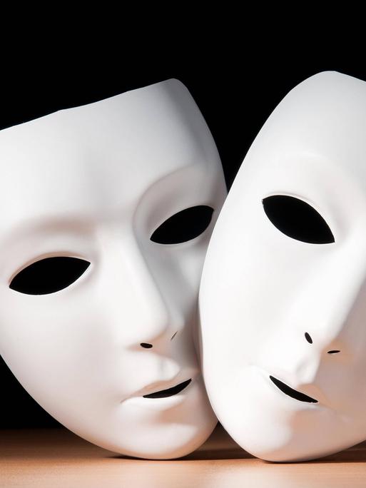 Zwei weiße Gesichtsmasken vor schwarzem Hintergrund