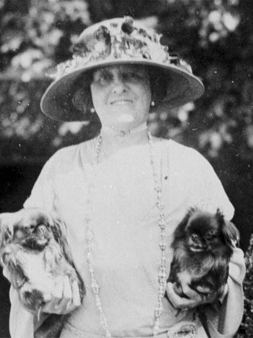 Die Schriftstellerin Edith Wharton auf einem schwarz-weiß Foto. Sie hält in jeder Hand einen kleinen Hund.