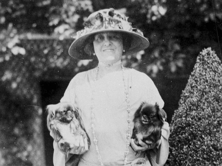 Die Schriftstellerin Edith Wharton auf einem schwarz-weiß Foto. Sie hält in jeder Hand einen kleinen Hund.