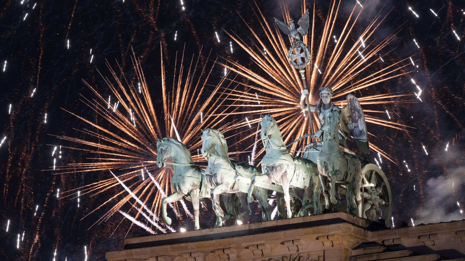Feuerwerk zum Jahreswechsel steigt während der Silvester-Feier hinter dem Brandenburger Tor auf.