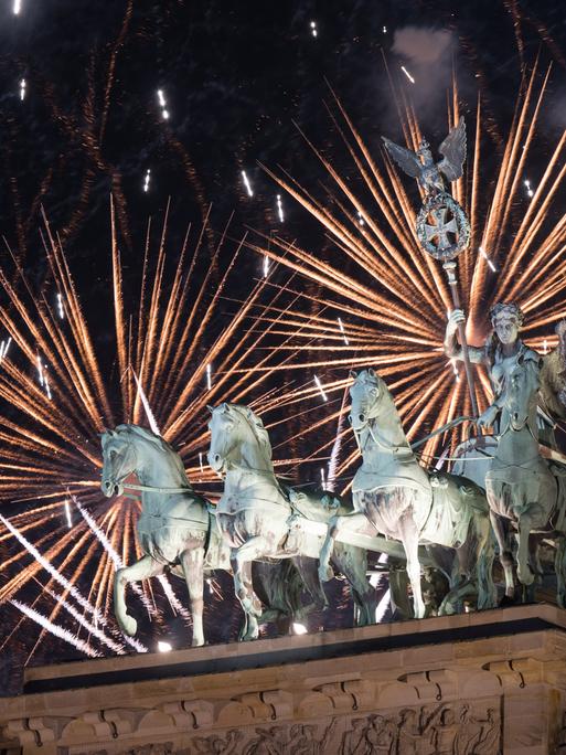 Feuerwerk zum Jahreswechsel steigt während der Silvester-Feier hinter dem Brandenburger Tor auf.