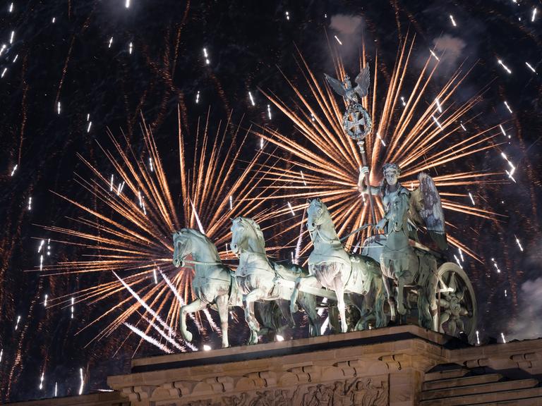 Feuerwerk zum Jahreswechsel steigt während der Silvester-Feier hinter dem Brandenburger Tor auf.