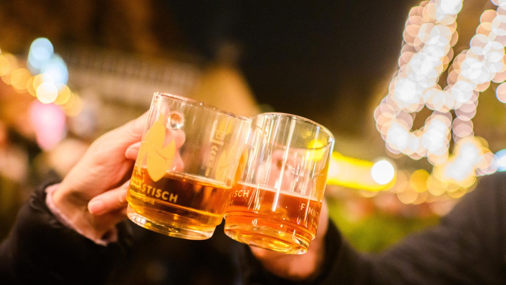 Besucher stoßen mit weißem Glühwein auf dem Weihnachtsmarkt an.