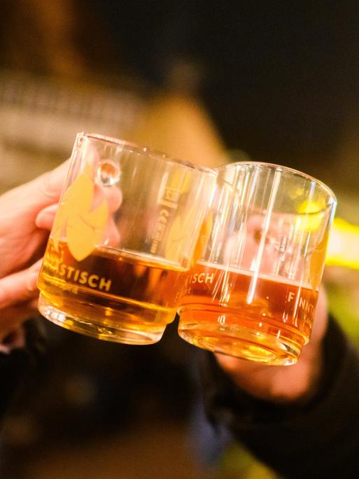 Besucher stoßen mit weißem Glühwein auf dem Weihnachtsmarkt an.