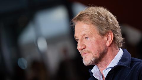 Der Regisseur Sönke Wortmann kommt über den Roten Teppich zur Premiere des Kinofilms "Eingeschlossene Gesellschaft". Er trägt einen blauen Pullover und darunter ein Hemd.