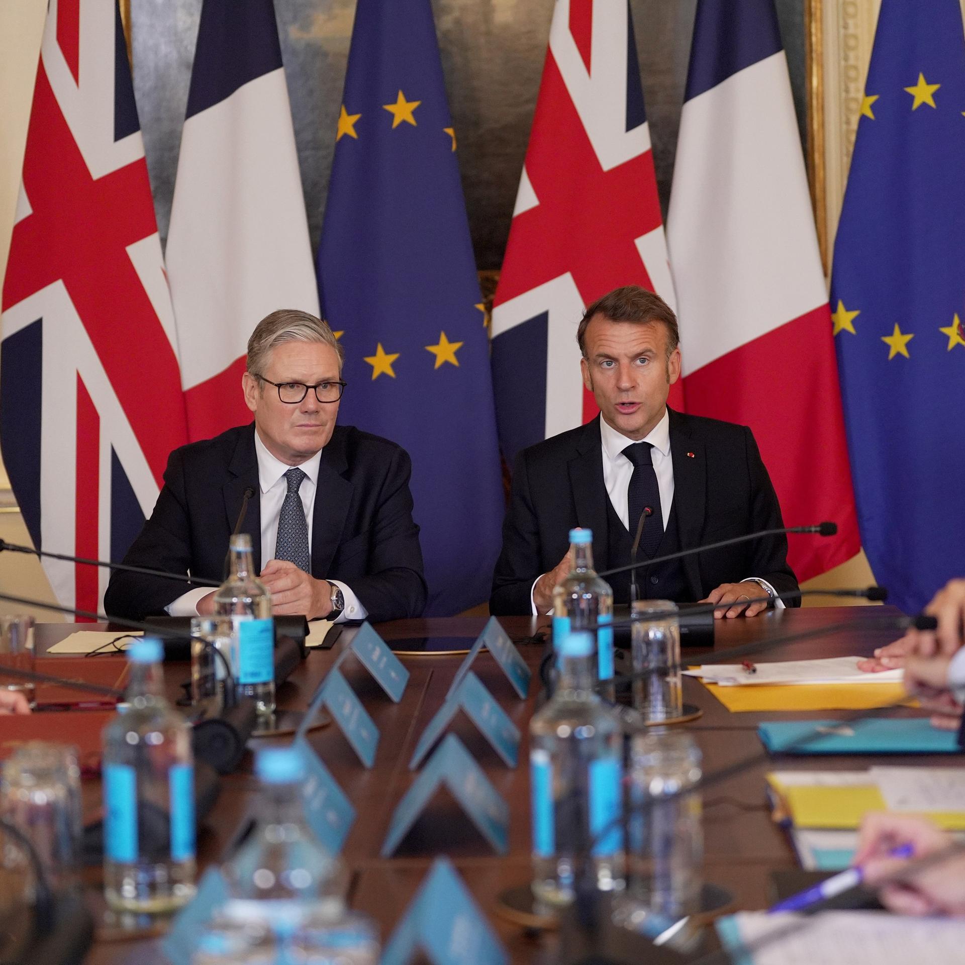 Der britische Premierminister Starmer und Frankreichs Präsident Macron sitzen nebeneinander, hinter ihnen die Landes- und die EU-Flagge. Der britische Premierminister Starmer und Frankreichs Präsident Macron sitzen nebeneinander, hinter ihnen die Landes- und die EU-Flagge.