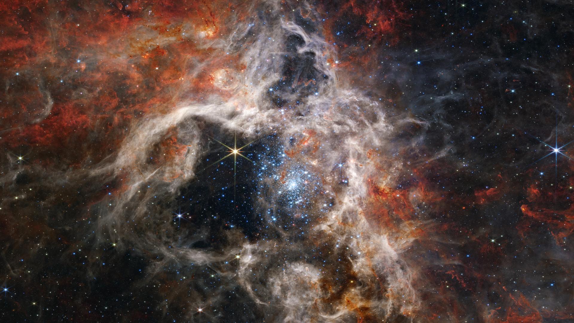 Ein farbenfrohes Weltraumbild mit hellen Sternen und großen rot-weißen Wolken aus Gas und Staub. Ein farbenfrohes Weltraumbild mit hellen Sternen und großen rot-weißen Wolken aus Gas und Staub.