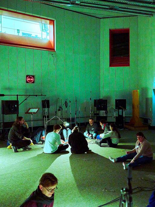 Eine Gruppe von Mensche sitzen im großen Hörspielstudio auf der Erde - Vorbereitungen zu "Making of Menschheit"