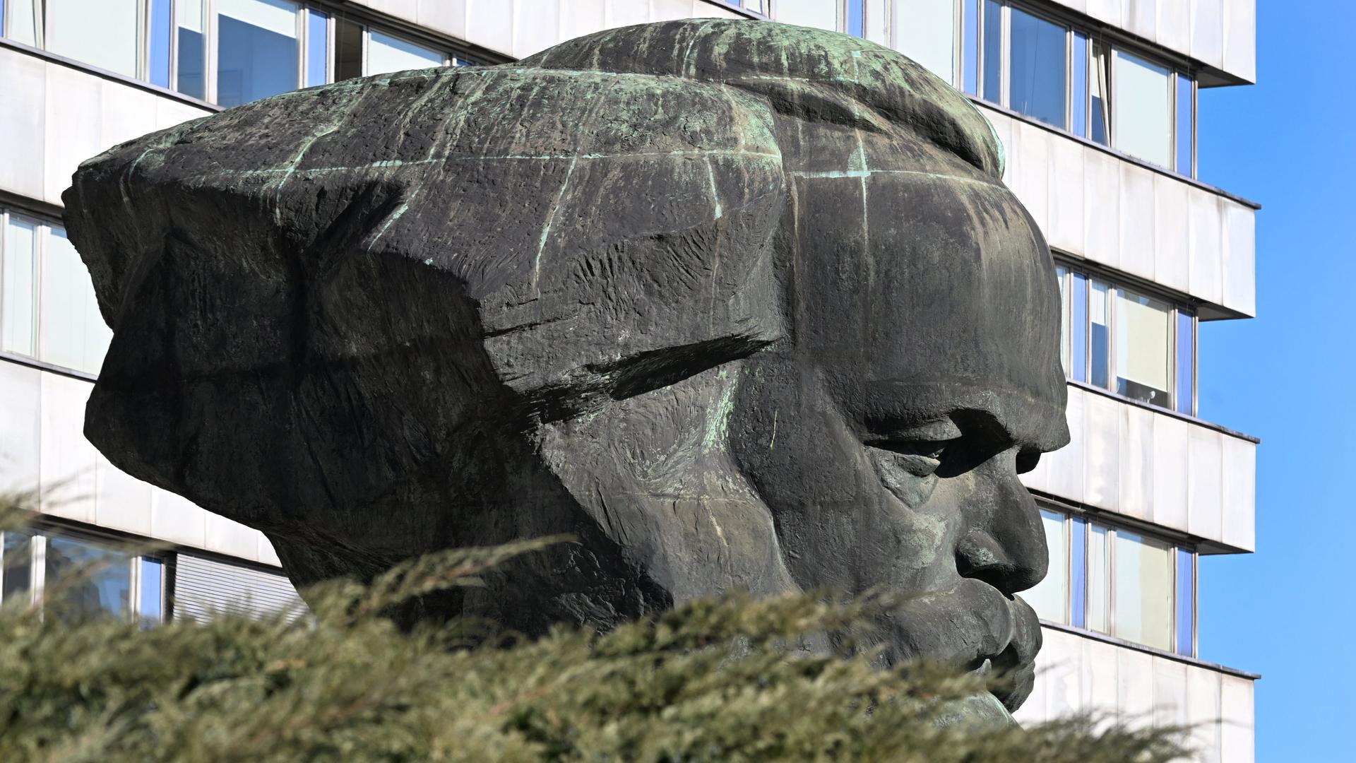 Das Karl-Marx-Monument in Chemnitz von der Seite gesehen mit einem Plattenbau im Hintergrund. 