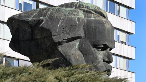 Das Karl-Marx-Monument in Chemnitz von der Seite gesehen mit einem Plattenbau im Hintergrund. 