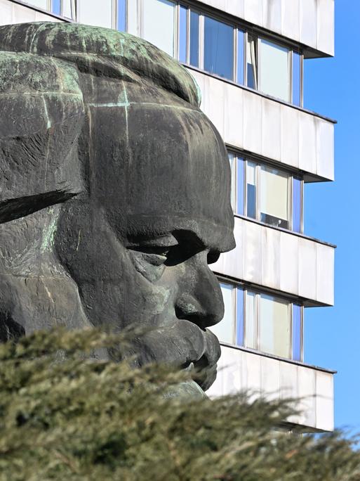 Das Karl-Marx-Monument in Chemnitz von der Seite gesehen mit einem Plattenbau im Hintergrund. 