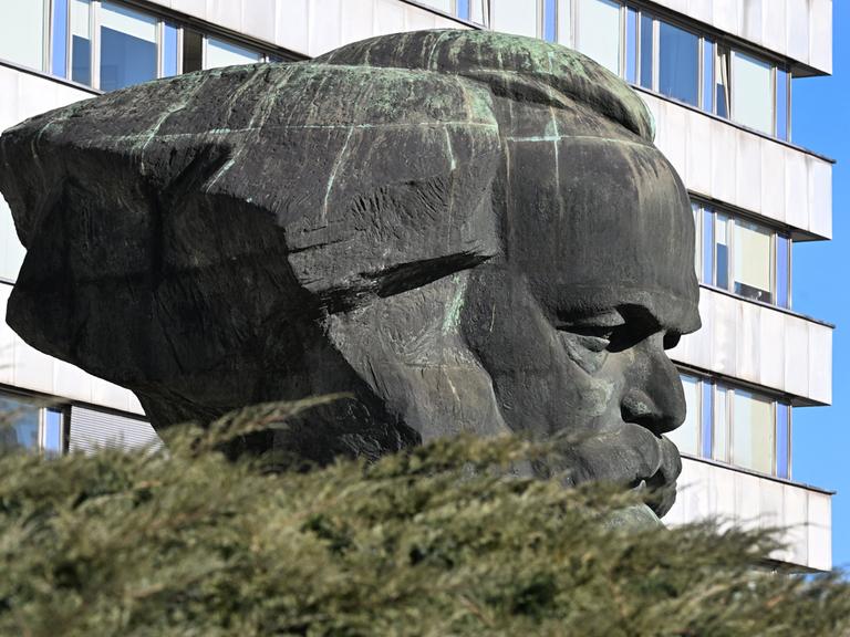 Das Karl-Marx-Monument in Chemnitz von der Seite gesehen mit einem Plattenbau im Hintergrund. 