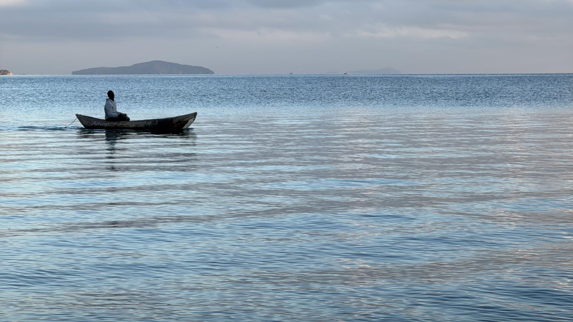 Ein Fischer auf dem Malawisee. Das Wasser ist ruhig und das kleine Boot treibt dahin. Ein Fischer auf dem Malawisee. Das Wasser ist ruhig und das kleine Boot treibt dahin.