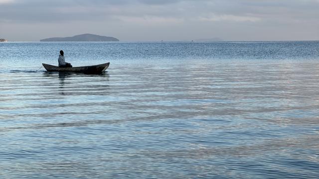 Ein Fischer auf dem Malawisee. Das Wasser ist ruhig und das kleine Boot treibt dahin.