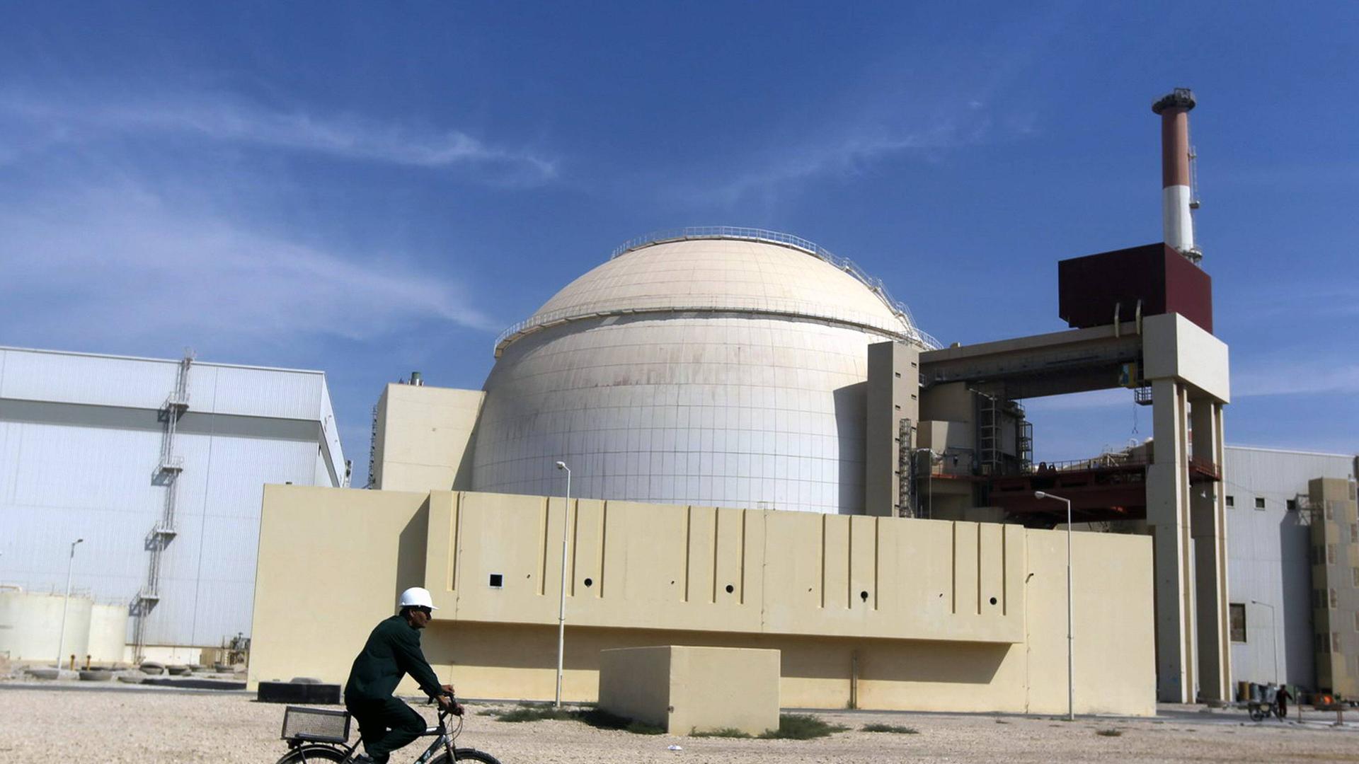 Arbeiter auf einem Fahrrad vor dem Atommeiler von Bushehr im Iran