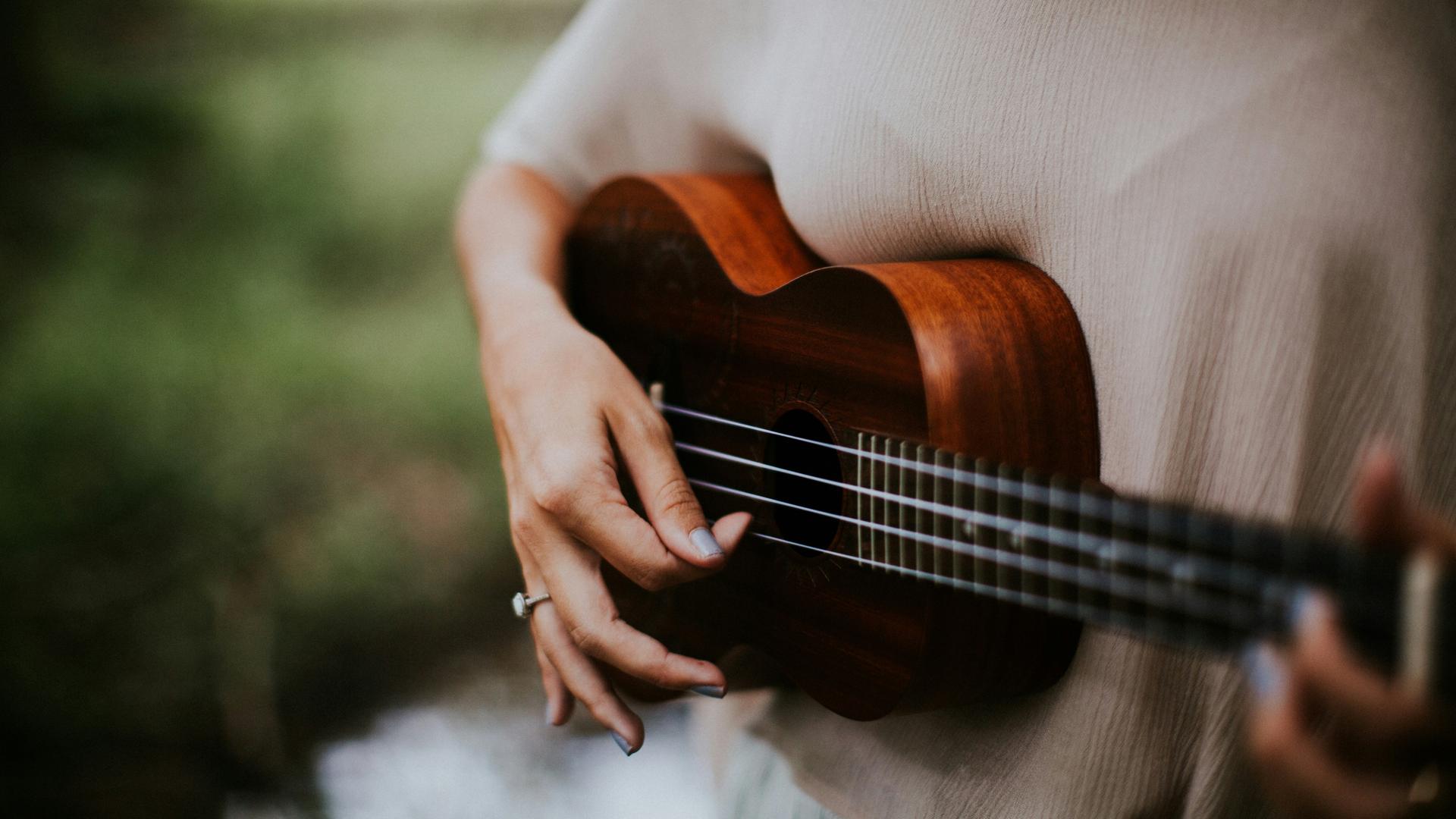 Blick auf eine Frauenhand, die Ukulele spielt.