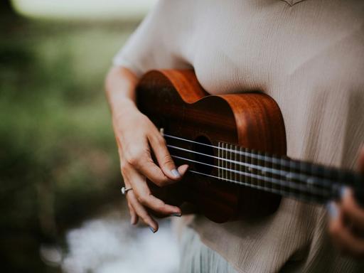 Blick auf eine Frauenhand, die Ukulele spielt.