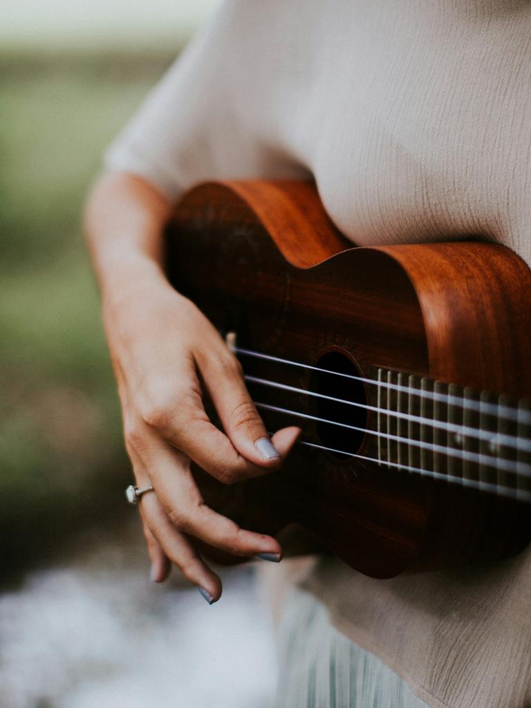 Blick auf eine Frauenhand, die Ukulele spielt.