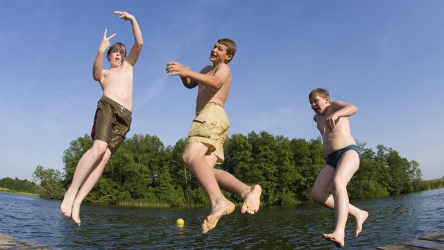Drei befreundete Jungen springen von einem Steg im brandenburgischen Beeskow in einen See
