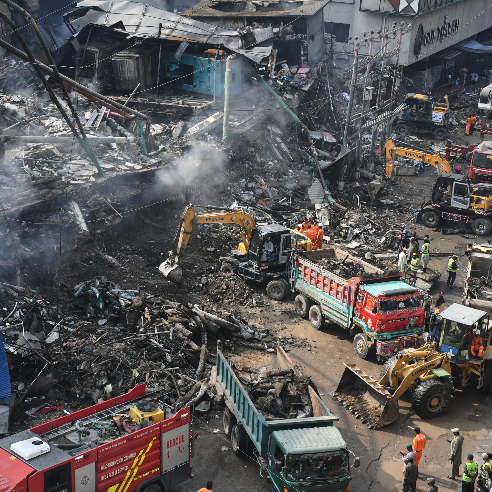 Karachi: Rettungskräfte und Feuerwehrleute durchsuchen mit schwerem Gerät die Trümmer eines abgebrannten Gebäudes in einem mehrstöckigen Einkaufszentrum nach einem Großbrand.