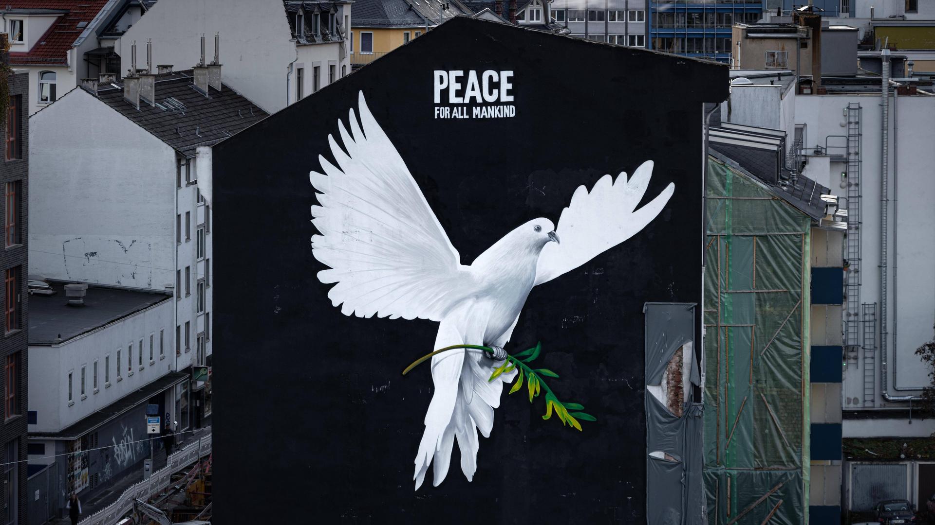 „PEACE FOR ALL MANKIND“ („Frieden für die ganze Menschheit“) steht über dem Bild einer riesigen Friedenstaube an einer Hauswand in Frankfurt am Main. 