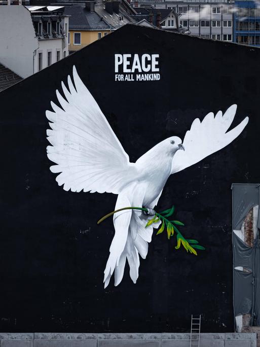 „PEACE FOR ALL MANKIND“ („Frieden für die ganze Menschheit“) steht über dem Bild einer riesigen Friedenstaube an einer Hauswand in Frankfurt am Main. „PEACE FOR ALL MANKIND“ („Frieden für die ganze Menschheit“) steht über dem Bild einer riesigen Friedenstaube an einer Hauswand in Frankfurt am Main.