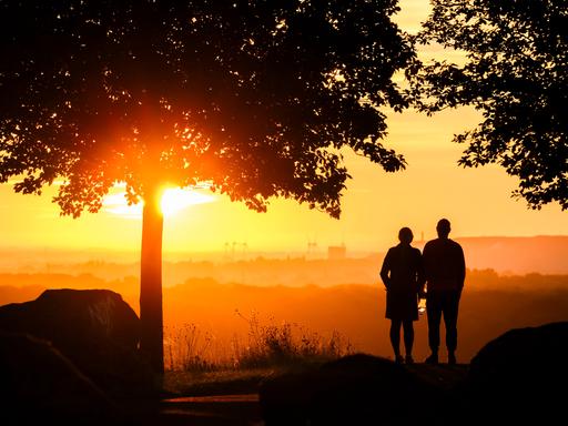 Ein Paar steht bei Sonnenaufgang auf dem Kronsberg bei Hannover