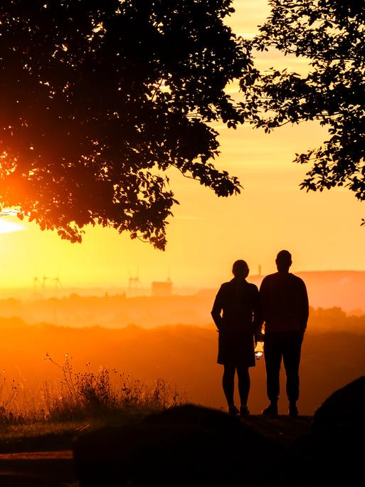 Ein Paar steht bei Sonnenaufgang auf dem Kronsberg bei Hannover