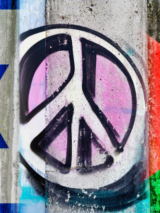 Auf einer Mauer sind Fahnen Israels und Palästinas zu sehen, in der Mitte zwischen beiden prangt ein Peace-Zeichen. 