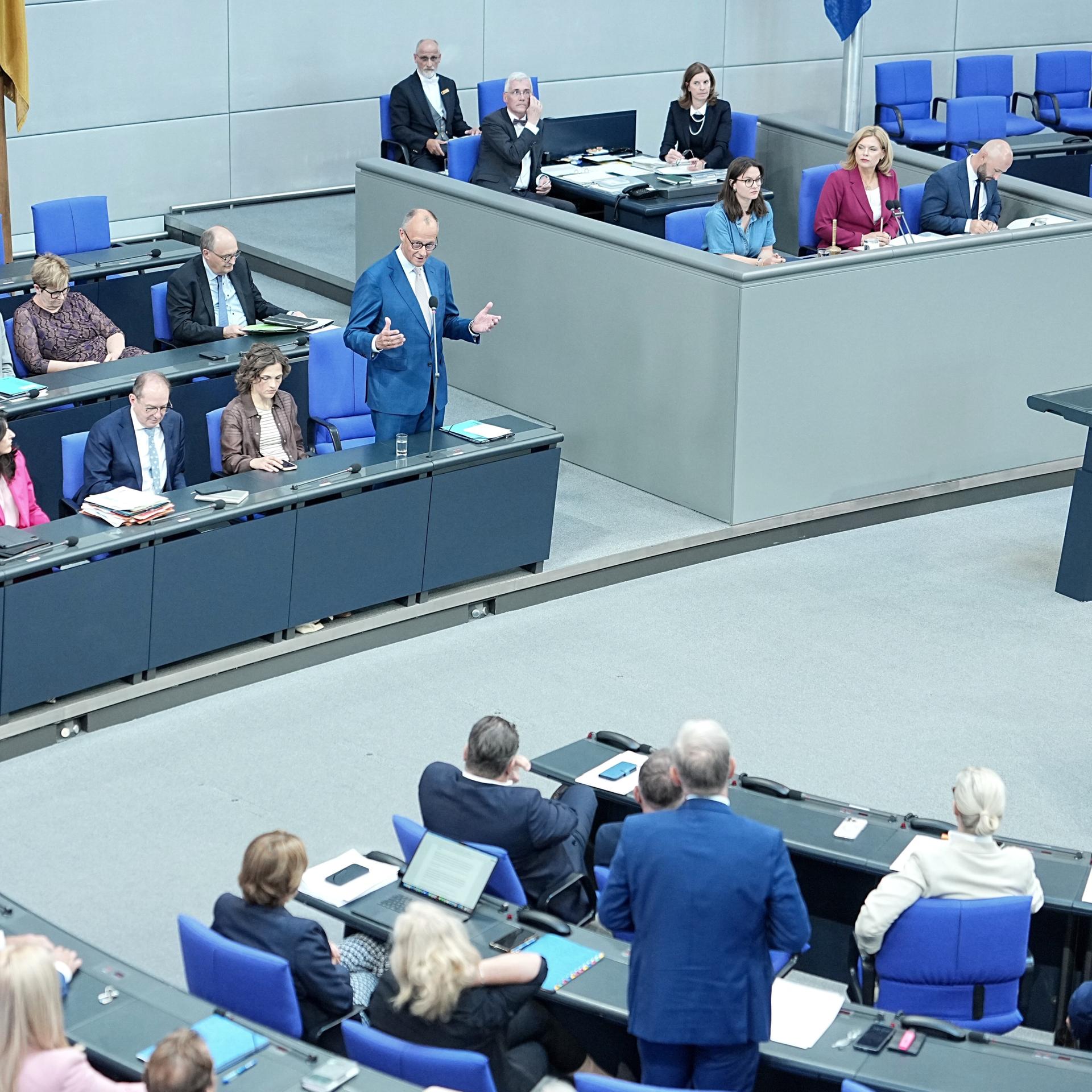 Bundeskanzler Friedrich Merz (CDU, hinten, M,l) spricht im Plenum des Bundestags bei der Regierungsbefragung.