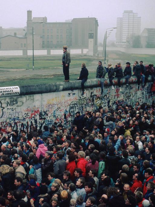 Menschenmasse vor und auf der Berliner Mauer. Grenzöffnung am 9. November 1989.