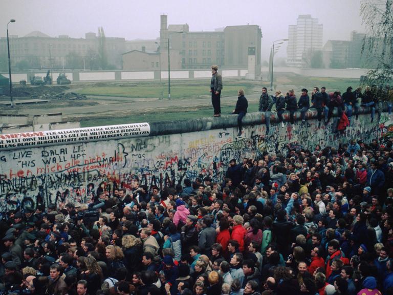 Menschenmasse vor und auf der Berliner Mauer im November 1989.