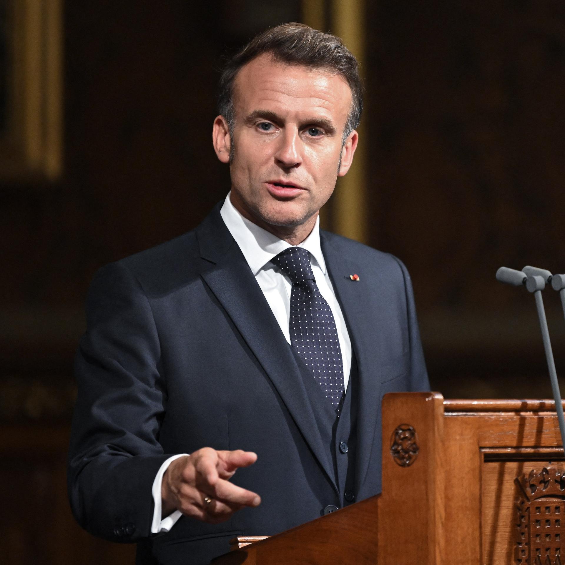 Frankreichs Präsident Macron steht vor dem Parlament in London hinter einem Rednerpult, er gestikuliert mit der rechten Hand.