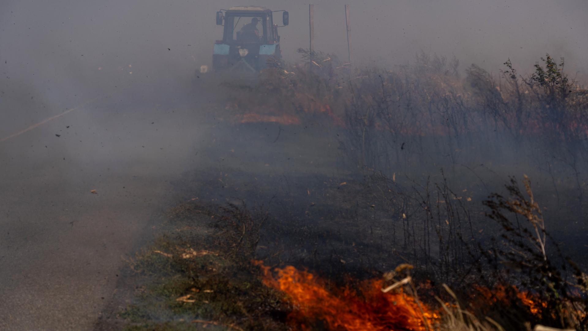 Ein ukrainischer Bauer versucht, nach einem russischen Angriff ein Feuer auf einem Feld zu löschen.