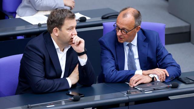 Bundesfinanzminister Lars Klingbeil (SPD) und Bundeskanzler Friedrich Merz (CDU) sitzen im Bundestag nebeneinander und sind in ein Gespräch vertieft.