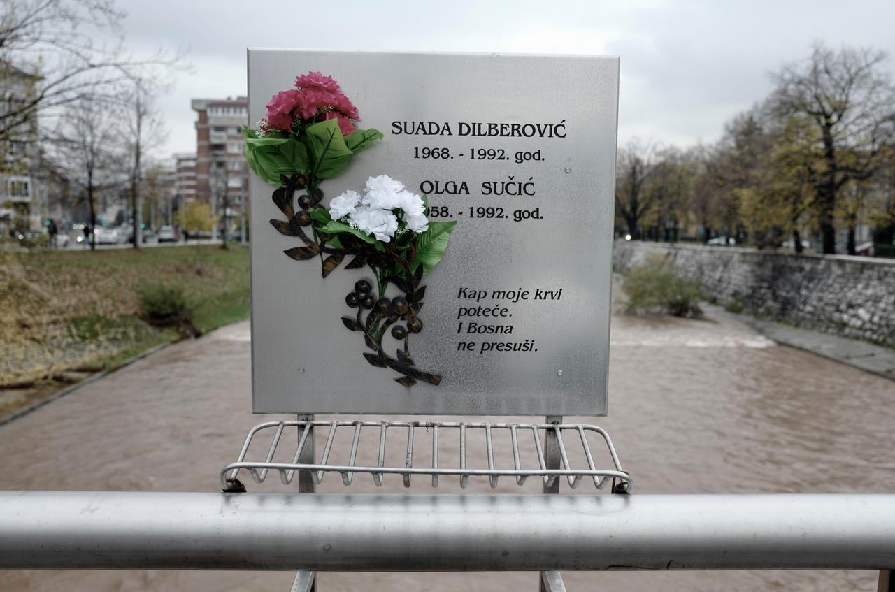 Eine mit Blumen geschmückte Gedenktafel auf einer Brücke in Sarajevo.