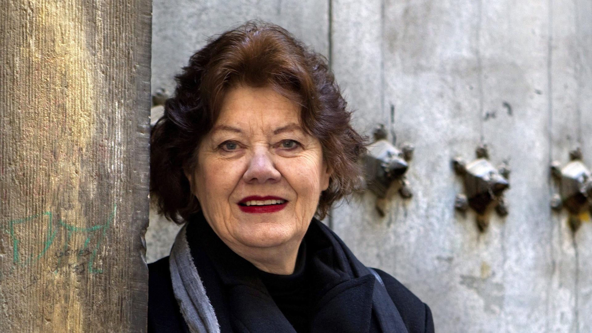 Die britische Autorin Anne Perry steht vor einer steinernen Wand