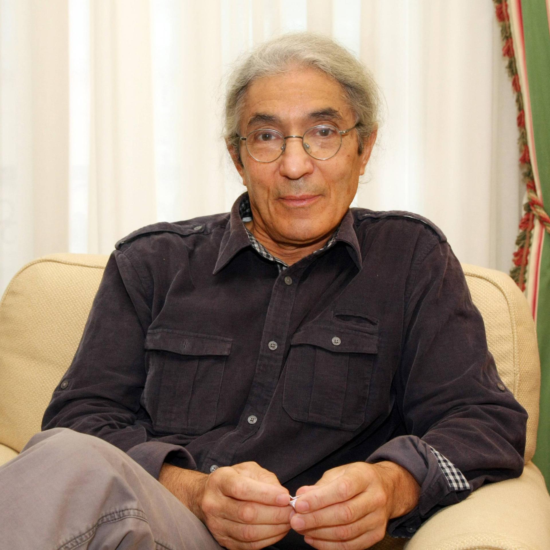 Der algerische Schriftsteller Boualem Sansal bei einem epd-Gespräch am 11.10.2011 in Frankfurt am Main. Er trägt ein dunkles Hemd, Brille und sitzt vor Vorhängen auf einem hellen Sessel.