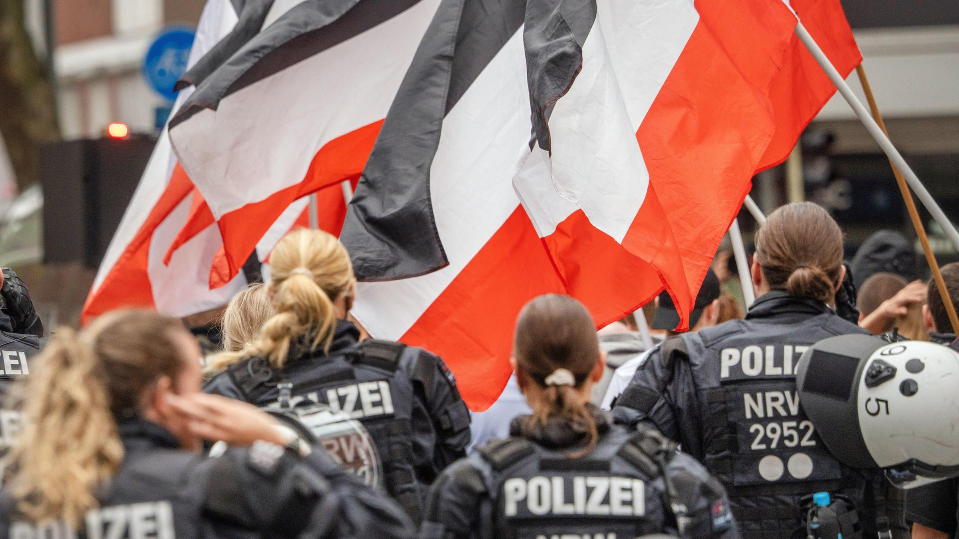 Polizeibeamte sichern eine rechtsextreme Demonstration in Münster mit Teilnehmern, die Reichsflaggen in Schwarz-Weiß-Rot tragen. Polizeibeamte sichern eine rechtsextreme Demonstration in Münster mit Teilnehmern, die Reichsflaggen in Schwarz-Weiß-Rot tragen.