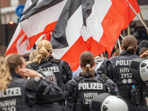 Polizeibeamte sichern eine rechtsextreme Demonstration in Münster mit Teilnehmern, die Reichsflaggen in Schwarz-Weiß-Rot tragen. Polizeibeamte sichern eine rechtsextreme Demonstration in Münster mit Teilnehmern, die Reichsflaggen in Schwarz-Weiß-Rot tragen.