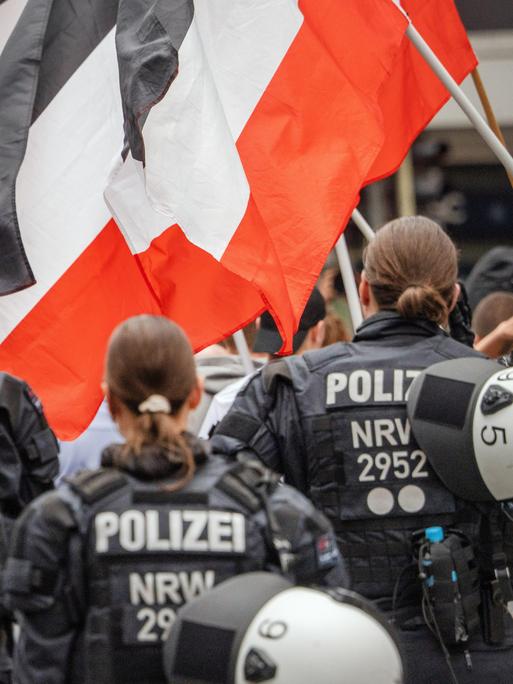 Polizeibeamte sichern eine rechtsextreme Demonstration in Münster mit Teilnehmern, die Reichsflaggen in Schwarz-Weiß-Rot tragen. Polizeibeamte sichern eine rechtsextreme Demonstration in Münster mit Teilnehmern, die Reichsflaggen in Schwarz-Weiß-Rot tragen.