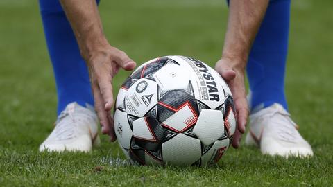 Ein Fußballprofi legt sich den Ball auf den Elfmeterpunkt.