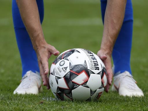 Ein Fußballprofi legt sich den Ball auf den Elfmeterpunkt.