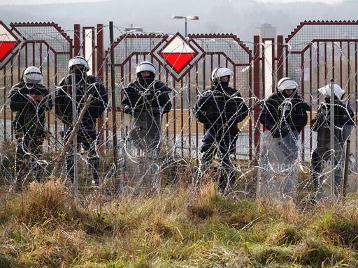 Polnische Sicherheitskräfte stehen an der Grenze zu Belarus hinter Stacheldraht. Polnische Sicherheitskräfte stehen an der Grenze zu Belarus hinter Stacheldraht.