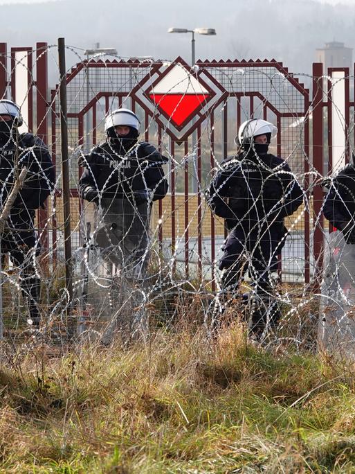 Polnische Sicherheitskräfte stehen an der Grenze zu Belarus hinter Stacheldraht.
