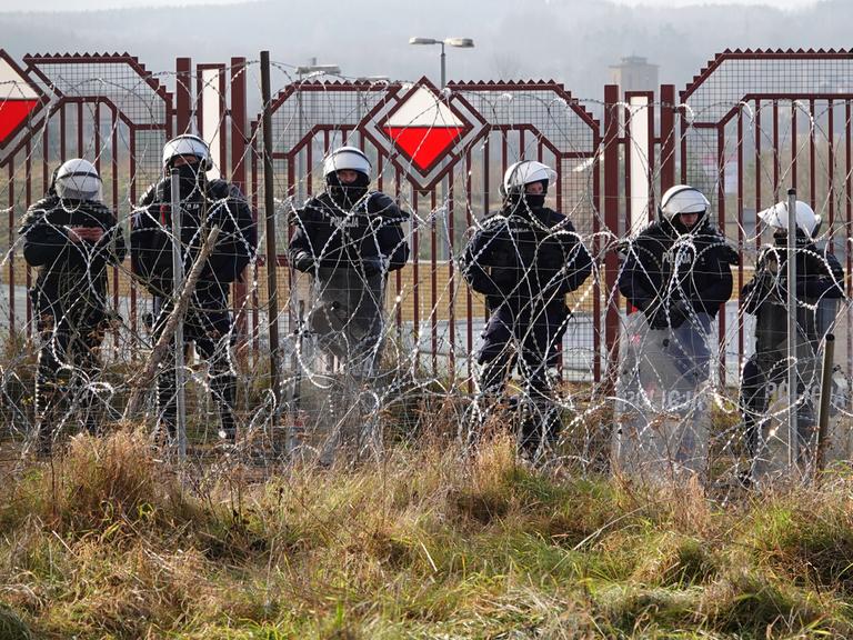 Polnische Sicherheitskräfte stehen an der Grenze zu Belarus hinter Stacheldraht.