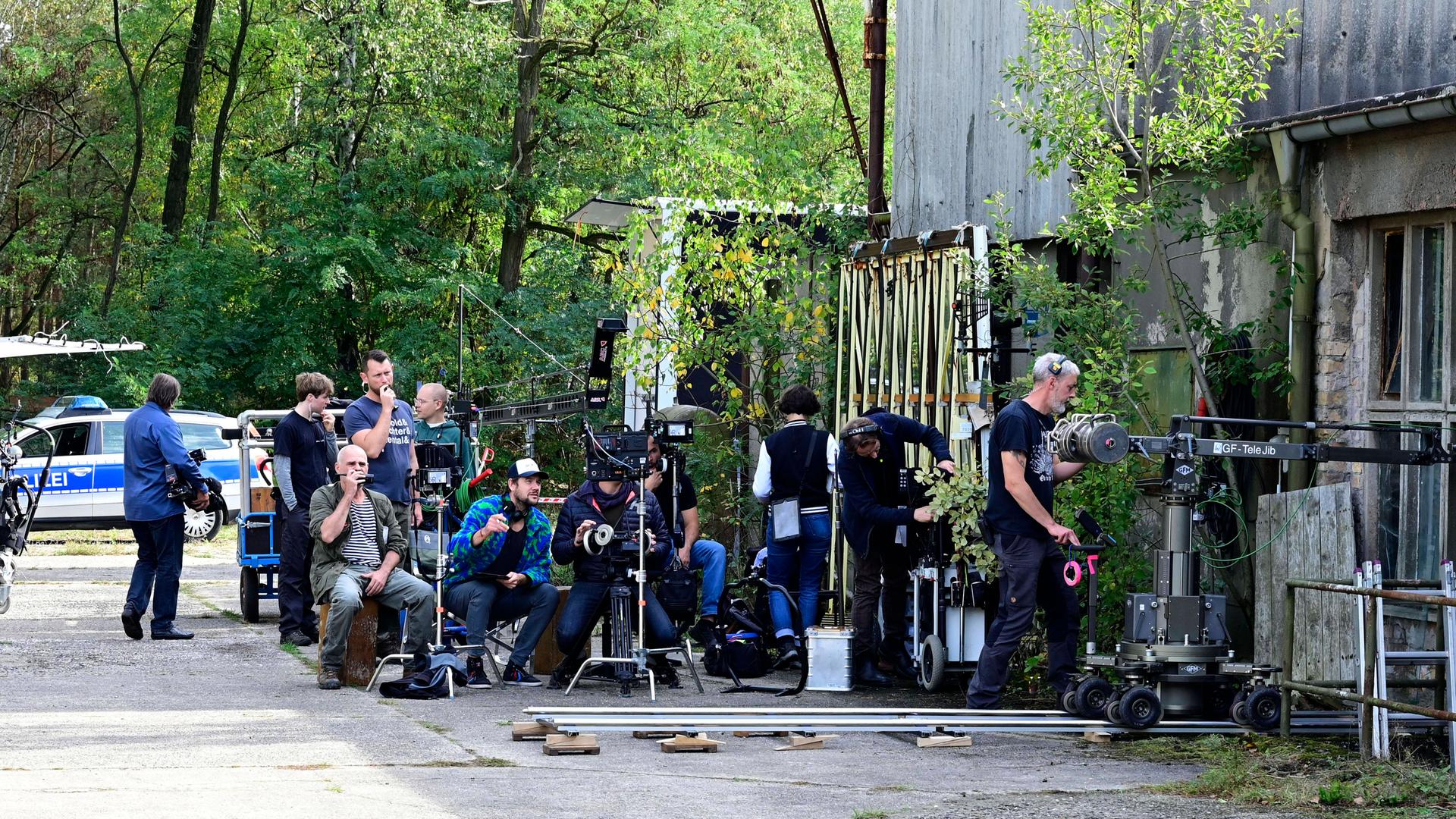 Ein Filmteam nimmt von außen Szenen innerhalb eines Gebäudes auf. Hinter der Kamera stehen viele Menschen mit ihren Arbeitsgeräten. Ein Filmteam nimmt von außen Szenen innerhalb eines Gebäudes auf. Hinter der Kamera stehen viele Menschen mit ihren Arbeitsgeräten.