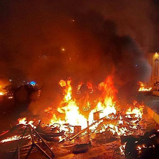 Ein Feuer auf Trümmern in einer dunklen Umgebung.