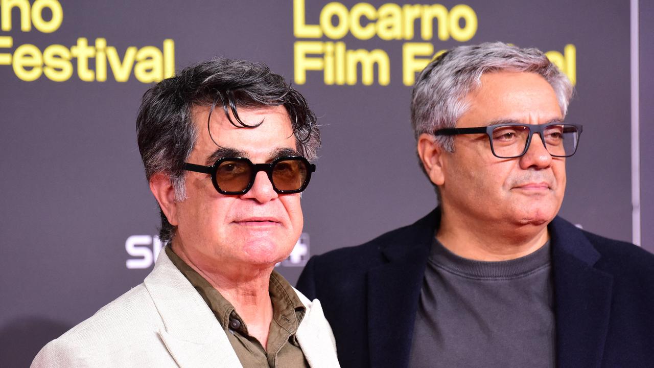 Jafar Panahi und Mohammad Rasoulof stehen nebeneinander vor einer Wand auf der "Locarno Filmfestival" steht. 